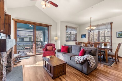 Living area featuring light wood-style floors, vaulted ceiling, a chandelier, a ceiling fan, and a fireplace with flush hearth