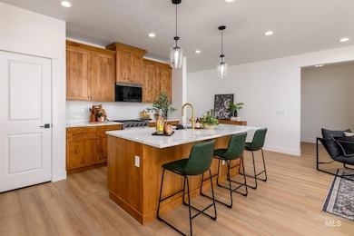 Kitchen featuring brown cabinetry, recessed lighting, backsplash, hanging light fixtures, and light wood-style flooring