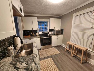 Kitchen with dark wood-style floors, white cabinetry, a textured ceiling, a sink, and appliances with stainless steel finishes