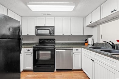 Kitchen with white cabinetry, a sink, light wood f