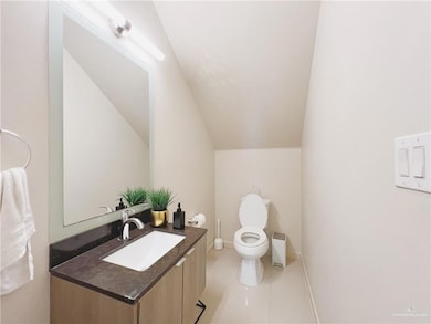 Bathroom with vanity, toilet, tile patterned floors, and lofted ceiling