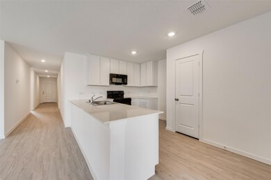 Kitchen with black appliances, white cabinetry, si