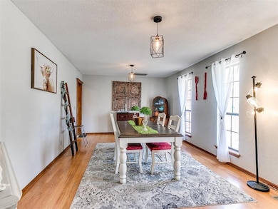 Dining space featuring a textured ceiling, light wood-type flooring, and baseboards