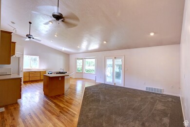 Kitchen with a center island, light countertops, vaulted ceiling, open floor plan, and light wood-type flooring