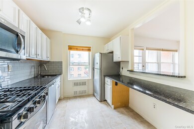 Kitchen featuring appliances with stainless steel finishes, dark stone counters, light tile patterned floors, and white cabinets