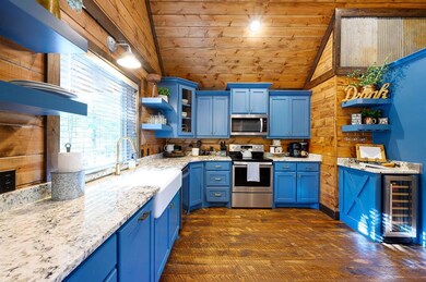 Kitchen featuring open shelves, blue cabinets, wood walls, vaulted ceiling, and light stone countertops