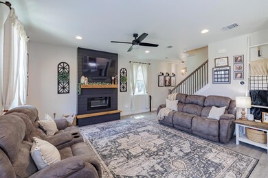 Living area with stairway, ceiling fan, a large f