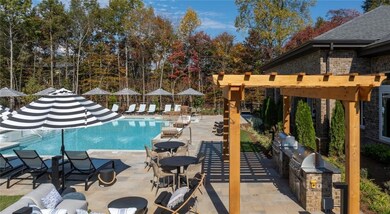 Community pool with exterior kitchen, a pergola, and a patio area