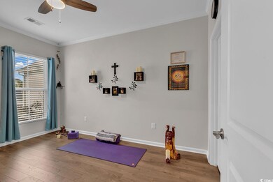 Exercise area featuring ornamental molding, visible vents, baseboards, and wood finished floors