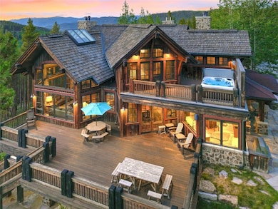 Back of property featuring a chimney, a deck with mountain view, a balcony, and stone siding