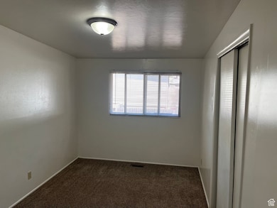 Empty room featuring dark carpet and baseboards
