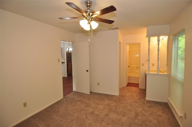 Unfurnished bedroom featuring carpet floors, a ceiling fan, and ensuite bath