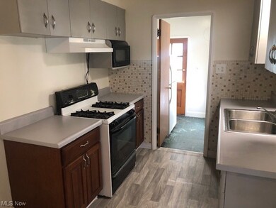 Kitchen with white gas range, light hardwood / wood-style floors, dark brown cabinets, and backsplash