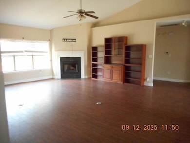 Unfurnished living room with a fireplace, lofted ceiling, dark wood-style floors, and ceiling fan