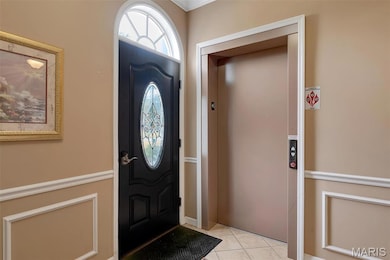Foyer featuring elevator and light tile patterned floors
