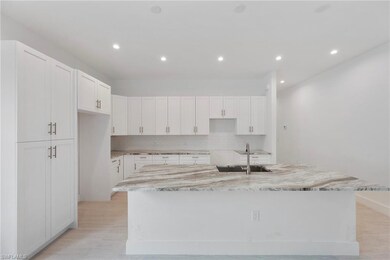 Kitchen with backsplash, white cabinetry, light stone counters, an island with sink, and recessed lighting