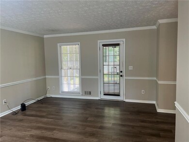 Empty room featuring dark wood-type flooring, a textured ceiling, and ornamental molding