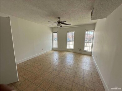Empty room featuring a textured ceiling, ceiling fan, and baseboards