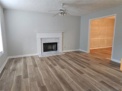 Unfurnished living room featuring wood finished floors, a high end fireplace, a ceiling fan, a textured ceiling, and baseboards