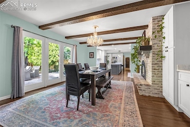 Dining area featuring a chandelier, wood finished floors, a fireplace, and beam ceiling