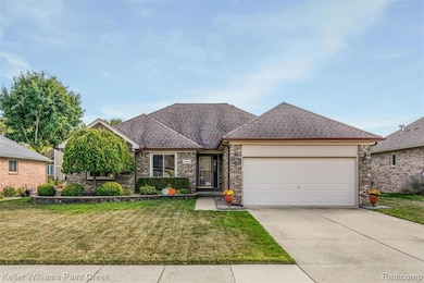 View of front of home with a shingled roof, a front yard, concrete driveway, a garage, and brick siding