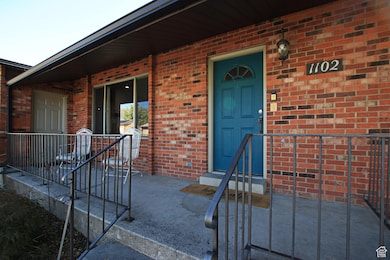 Doorway to property featuring brick siding and a porch