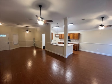 Unfurnished living room with a ceiling fan, ornamental molding, and dark wood-style flooring