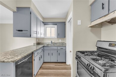 Kitchen with appliances with stainless steel finishes, sink, and light hardwood / wood-style flooring