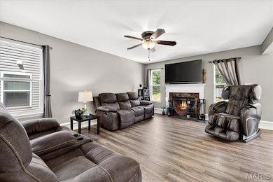 Living room featuring wood finished floors, a ceiling fan, and a glass covered fireplace