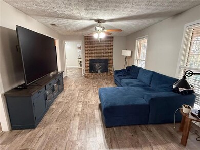 Living area featuring light wood finished floors, a textured ceiling, healthy amount of natural light, and a ceiling fan