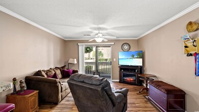 Living area featuring wood finished floors, ornamental molding, and a ceiling fan