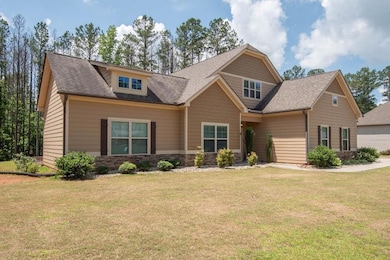 Craftsman-style home featuring a front lawn, a shingled roof, and stone siding