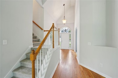 Foyer entrance with wood finished floors, stairs, and high vaulted ceiling