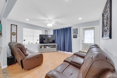 Living room featuring healthy amount of natural light, light tile patterned floors, ceiling fan, and recessed lighting