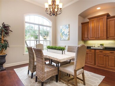 Elegant Formal Dining Room with Large arched window, crown molding, modern chandelier, wood floors and convenient serving station with storage and granite countertops.