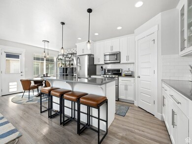 Kitchen with an island with sink, a kitchen bar, pendant lighting, decorative backsplash, and stainless steel appliances