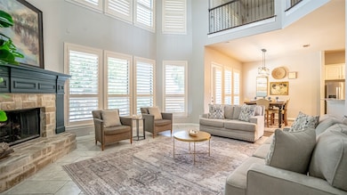 Living area with tile patterned floors, a stone fireplace, and a high ceiling