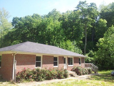 Solid red brick one story with new roof and replacement windows situated in a serene hollow.