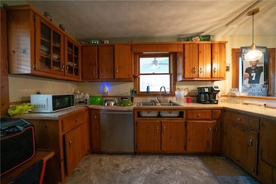 Kitchen with pendant lighting, a textured ceiling, stainless steel dishwasher, and sink