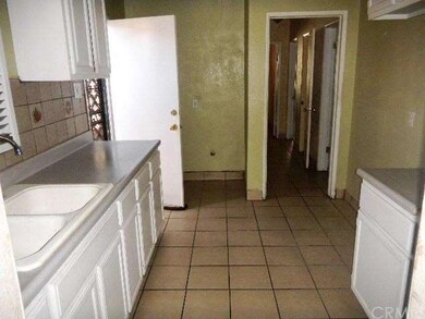 Kitchen view from living room. Door at left leads 