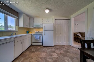 Kitchen with white cabinets, white appliances, til