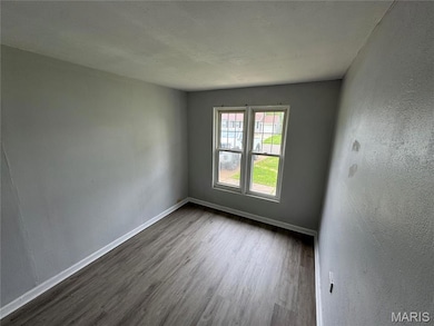 Spare room with wood finished floors and a textured wall