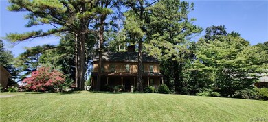 A large grassy front yard and mature trees surroun