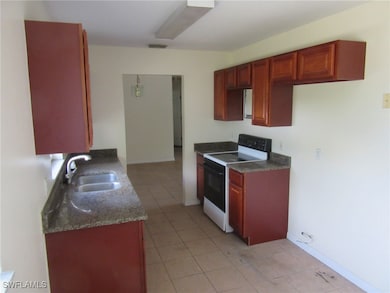 Kitchen with electric stove, a sink, and light til
