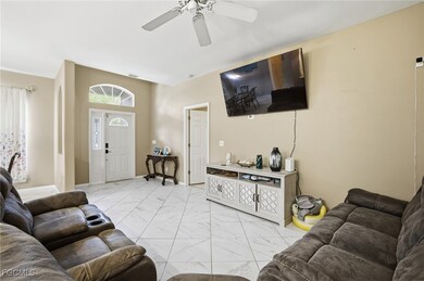 Living room featuring light marble finish floors and ceiling fan