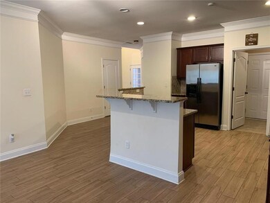 Kitchen with a kitchen island with sink, a kitchen breakfast bar, stainless steel refrigerator with ice dispenser, and light wood-style floors