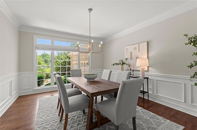 Refined separate formal dining room with custom trim, hardwoods, and lush views outside.
