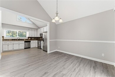 Kitchen featuring decorative backsplash, high vaulted ceiling, white cabinetry, pendant lighting, and light wood-style floors