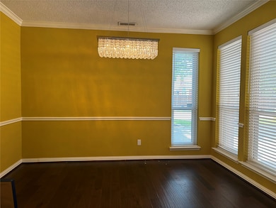 Unfurnished room with ornamental molding, dark wood-type flooring, a textured ceiling, and a chandelier