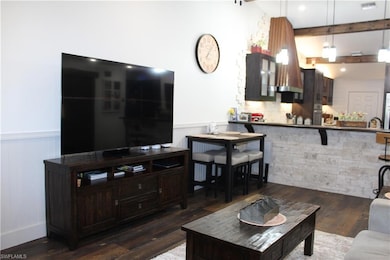 Living room featuring beamed ceiling and dark wood finished floors